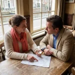 Marktonderzoeker en klant bespreken handgetekende kaart met kompas aan houten tafel in Amsterdam café