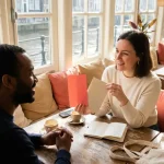Marketing professional vergelijkt koraalrode en beige kleurstalen met collega aan houten cafétafel in Amsterdam